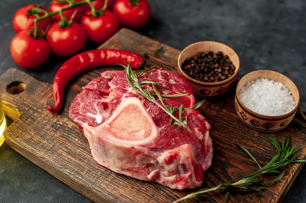 steak de boeuf cru avec os et épices sur fond de pierre