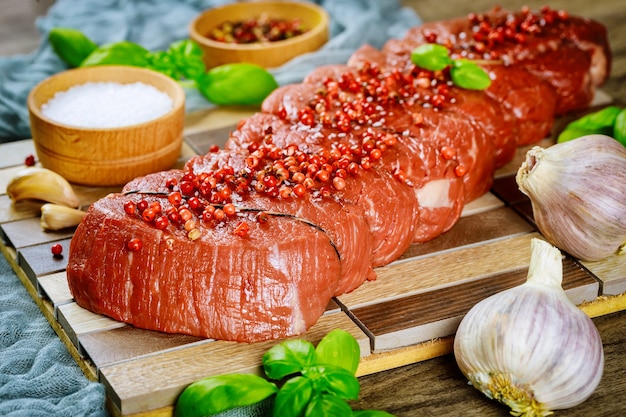 Steak de boeuf cru sur une planche à découper avec du basilic et des épices.