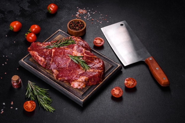 Steak de boeuf de flanc cru et ingrédients pour la cuisson sur une planche de bois se bouchent