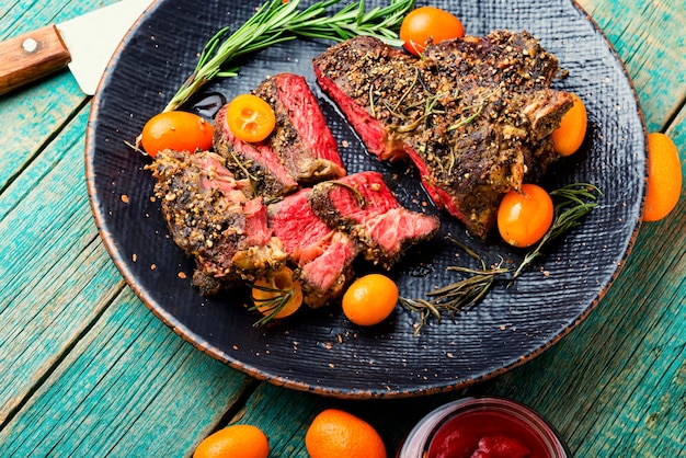 Steak de boeuf fraîchement tranché rôti au kumquat, romarin et épices. Entrecôte de veau sur une assiette