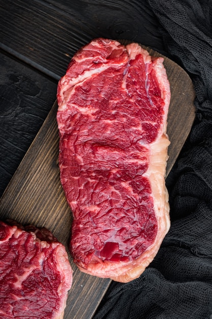 Steak de boeuf frais désossé club cru, sur table en bois noir, vue du dessus