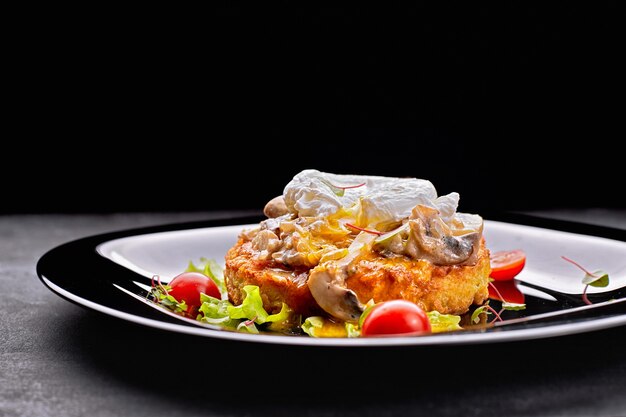 Steak de boeuf frit aux champignons, oeuf poché et tomates sur une plaque noire