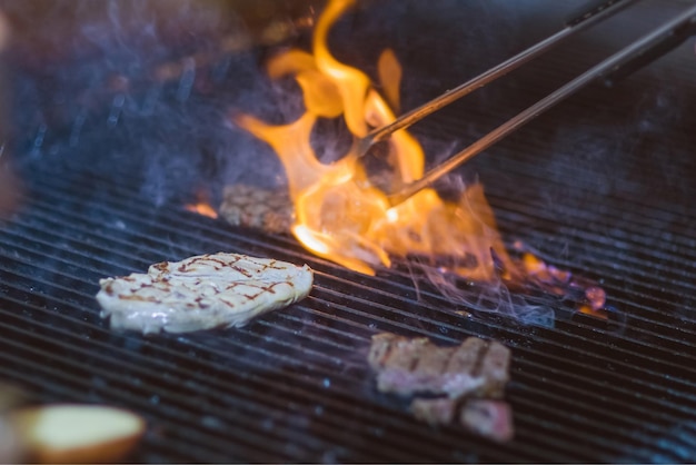 Steak de boeuf sur le grill avec de la fumée et des flammes