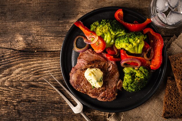 Steak de boeuf grillé avec beurre à l'ail et légumes. Viande au poivron grillé, brocoli et oignons.