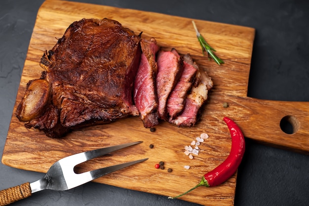 Steak de boeuf grillé sur une planche à découper sur un fond de pierre