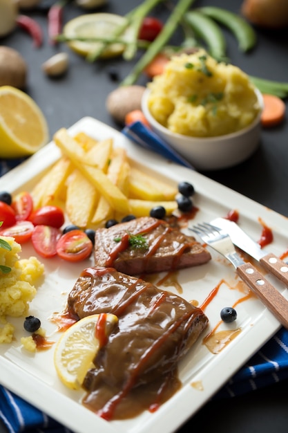 Steak de boeuf grillé sur plaque blanche frites et purée de pommes de terre