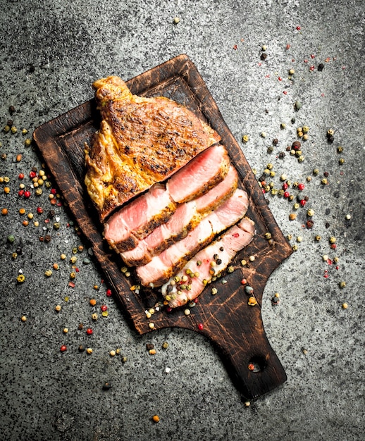 Steak de boeuf grillé sur un tableau noir avec des épices.