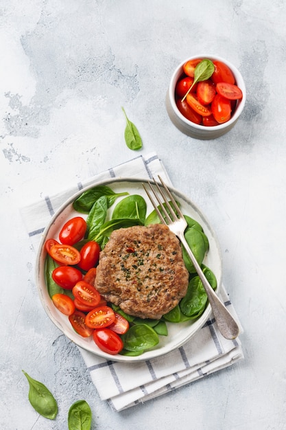 Steak de boeuf grillé avec tomates cerises et épinards, ail, assaisonnements, poivrons et oignons. Pleskavitsa plat traditionnel serbe. Vue de dessus