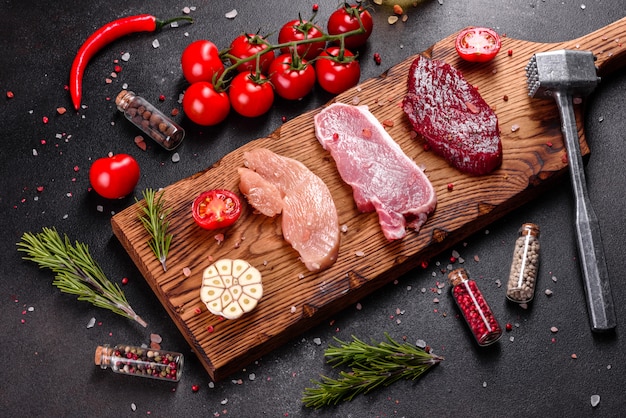 Steak de boeuf juteux frais, de porc et de poulet avec des légumes prêts à cuire. Steaks de différentes variétés de viande préparés pour la cuisson