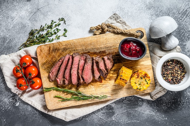 Steak de bœuf marbré Angus noir grillé tranché sur une planche à découper en bois.