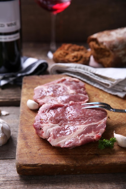 Steak de boeuf marbré avec une bouteille de vin et d'épices sur fond de bois