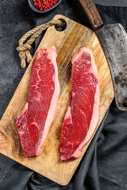 Steak de bœuf marbré cru sur une planche à découper.