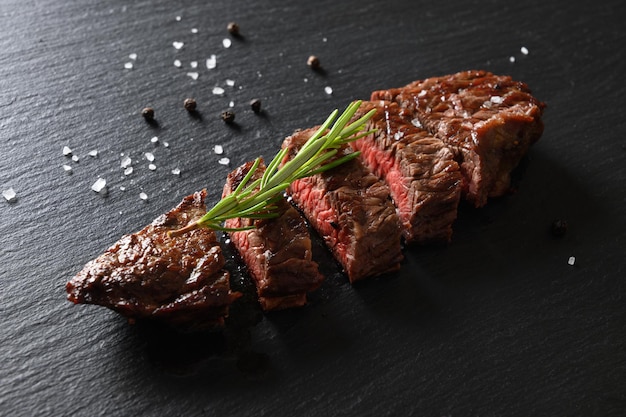 Steak de bœuf marbré frais grillé mi-saignant au romarin sur tableau noir