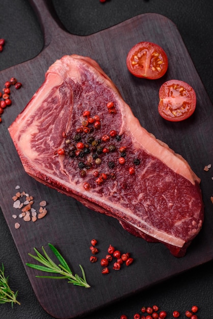 Steak de boeuf new york cru juteux frais avec des épices et des herbes salées