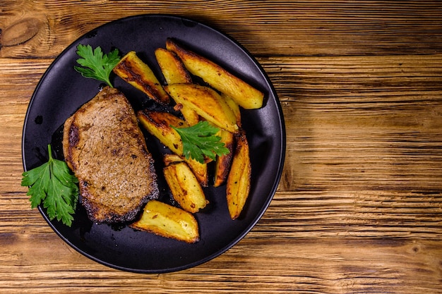Steak de boeuf rôti avec la pomme de terre frite et le persil. Vue de dessus