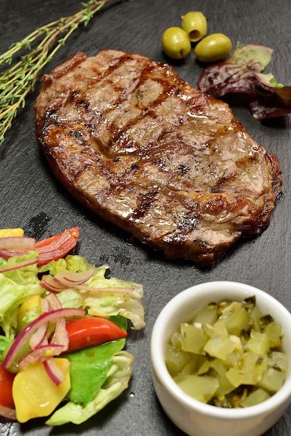 Steak de boeuf avec salade sur une plaque en ardoise