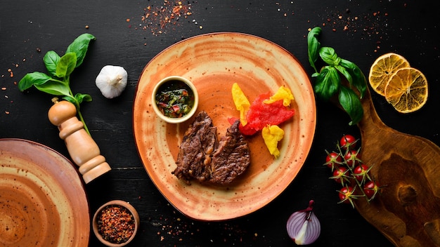 Steak de boeuf avec sauce sur une assiette. Sur un fond en bois noir. Vue de dessus. Espace de copie gratuit.