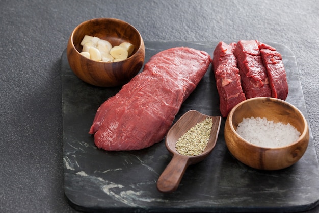 Steak de boeuf, sel et épices sur plaque d'ardoise noire