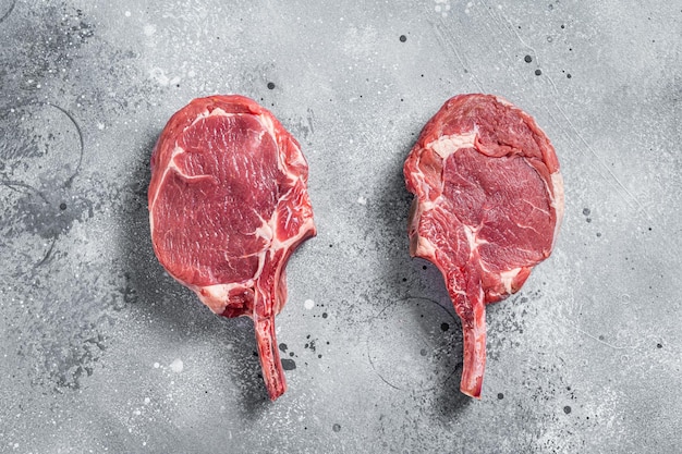 Steak de bœuf Tomahawk cru (veau) sur la table du boucher. Fond gris. Vue de dessus.
