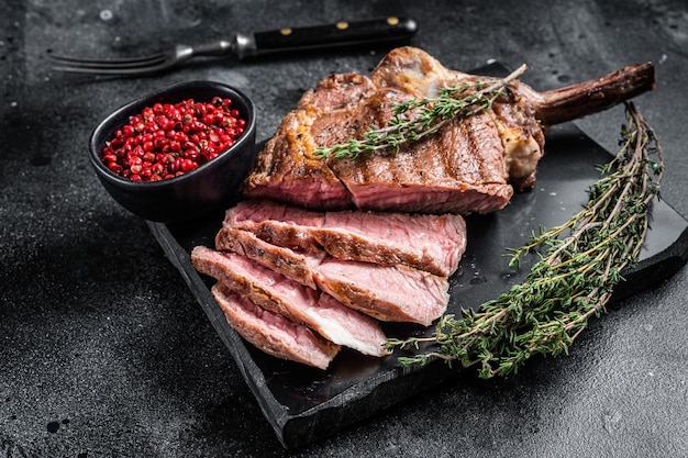 Steak de boeuf Tomahawk grillé, Entrecôte au thym. Fond noir. Vue de dessus.