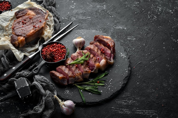 Steak de boeuf tranché grillé au romarin et épices sur fond de pierre noire Vue de dessus Espace libre pour votre texte