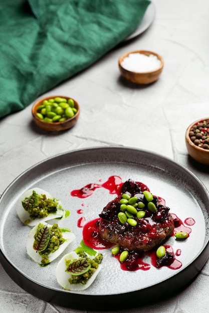 Steak de cerf avec sauce aux canneberges et pois verts sur plaque en céramique close up