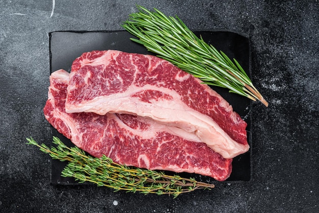 Steak de contre-filet cru ou viande de bœuf New York steak coupée. Fond noir. Vue de dessus.