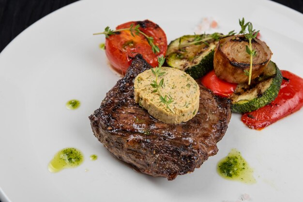 Steak de contre-filet noir angus grillé avec légumes sur plaque blanche sur fond de bois noir