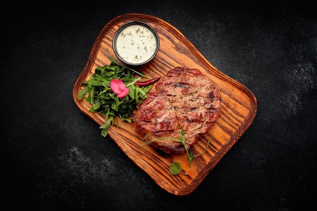 Steak de cou de porc avec sauce et roquette sur une planche de bois