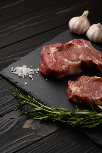 Steak de cow-boy cru et épices sur un fond en bois noir