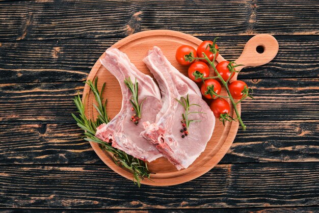 Steak cru sur l'os avec des épices et des légumes Sur un fond en bois Vue de dessus Espace de copie