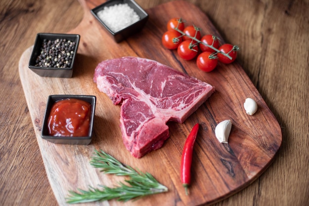 steak cru sur une planche à découper avec des herbes. Fond en bois.