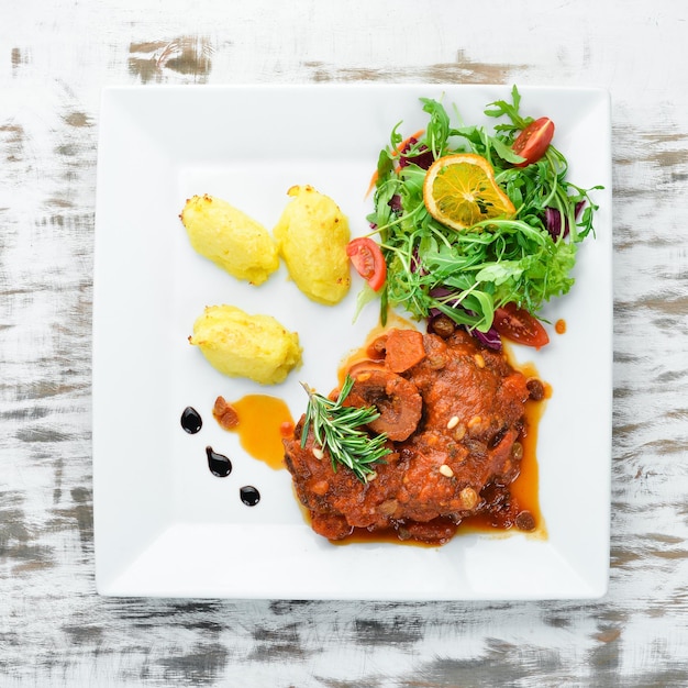 Steak cuit au four sur l'os avec sauce tomate et pommes de terre dans une assiette Vue de dessus Espace libre pour votre texte