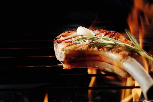 Steak cuit avec plat de cuisson sur un barbecue avec feu sur fond noir avec une place pour le texte et les inscriptions Gros plan