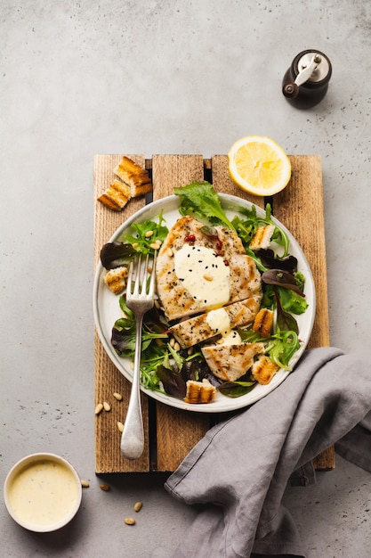 Steak de dinde grillé maison avec sauce, brocoli, roquette et blettes dans une assiette en céramique