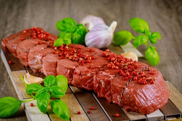 Steak de faux-filet cru avec de l'ail et des herbes sur un fond en bois.