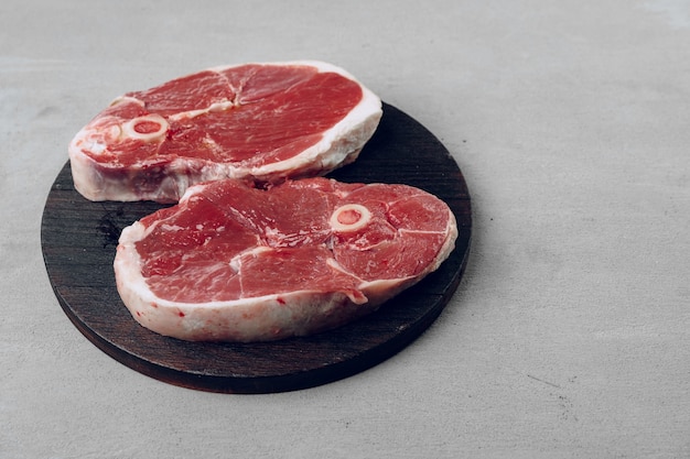 Steak de faux-filet cru sur planche à découper en bois sur fond gris close up