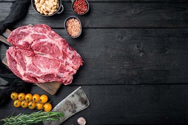 Photo steak de faux-filet nourri à l'herbe crue avec sel et poivre et ensemble d'herbes, et vieux couteau de couperet de boucher, sur une table en bois noir