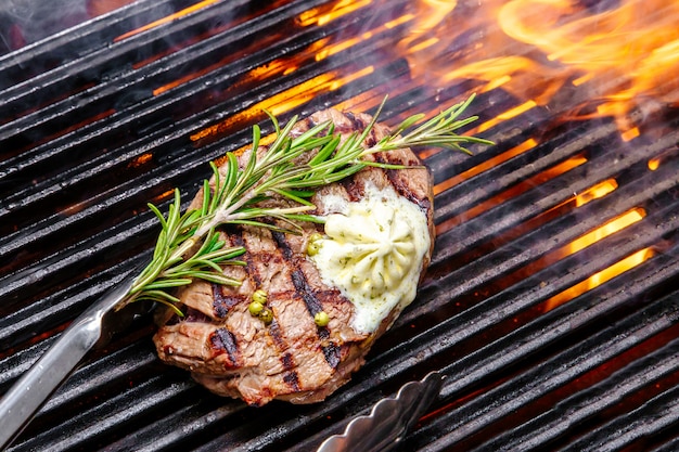 Steak sur un feu de gril, avec des herbes et du beurre