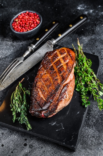 Steak de filet de canard rôti. Table noire. Vue de dessus. Copiez l'espace.