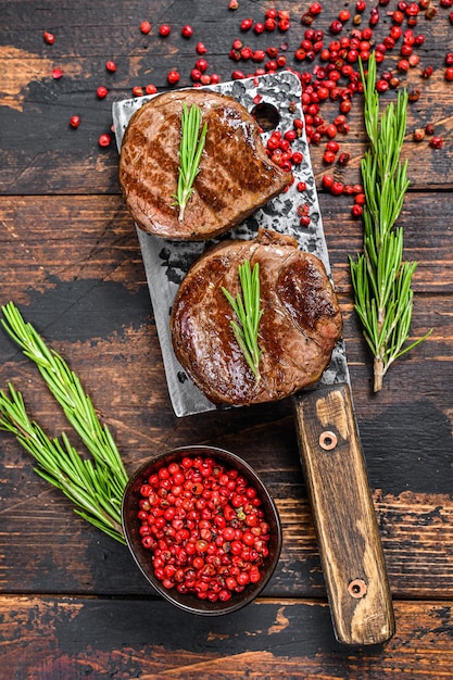 Steak de filet mignon grillé sur un couperet à viande. Fond en bois foncé. Vue de dessus.