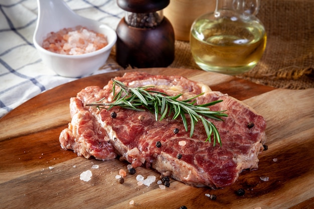 Steak frais sur une planche à découper en bois avec des ingrédients