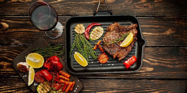 steak grillé aux épices et une bouteille de vin, un verre sur bois! Un dîner delicieux