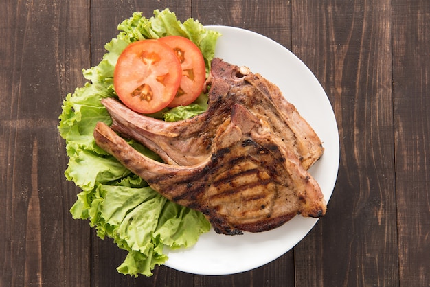 Steak grillé aux légumes sur un fond en bois.