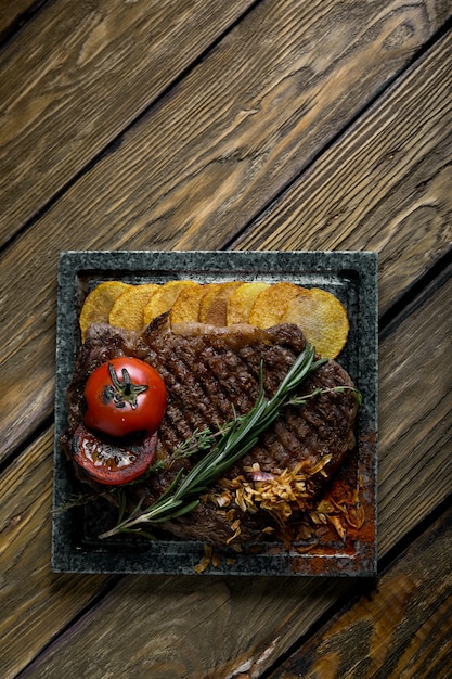 Photo steak grillé avec couteau et fourchette sculptés dans l'ardoise de pierre noire