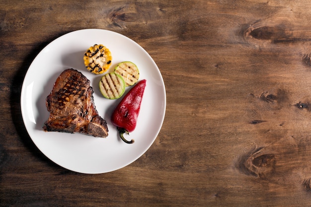 Steak grillé sur un fond en bois marron avec des légumes