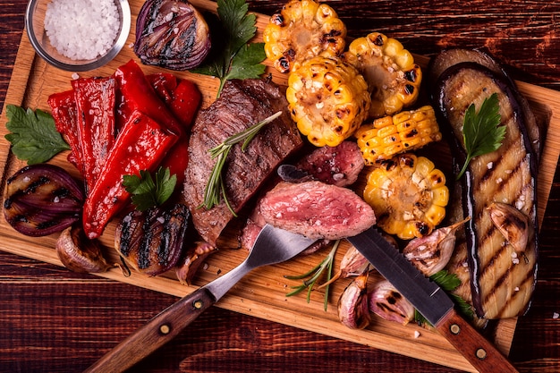 Steak grillé et légumes sur une planche à découper