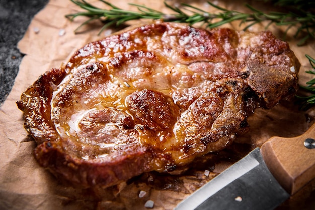 Steak grillé sur papier avec un couteau et un brin de romarin