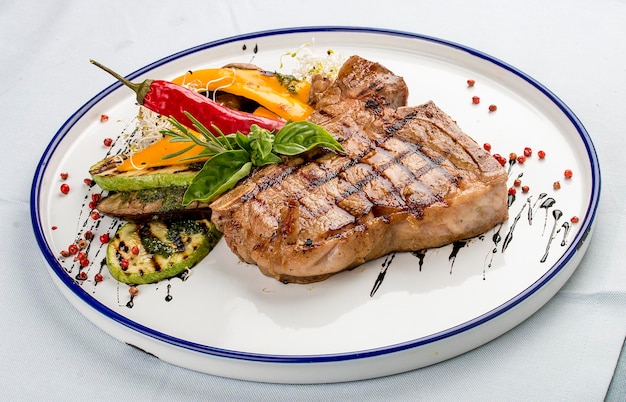 Steak grillé tendre ou steak Tbone servi avec des légumes grillés sur une assiette blanche