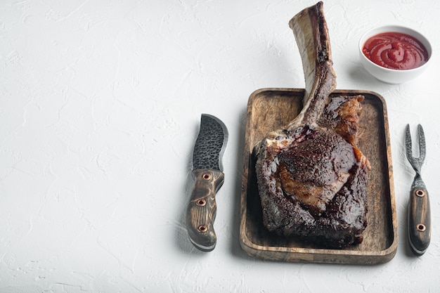 Steak juteux grillé sur l'ensemble de boeuf marbré tomahawk d'os, sur une planche de service en bois, sur fond de pierre blanche, avec espace de copie pour le texte